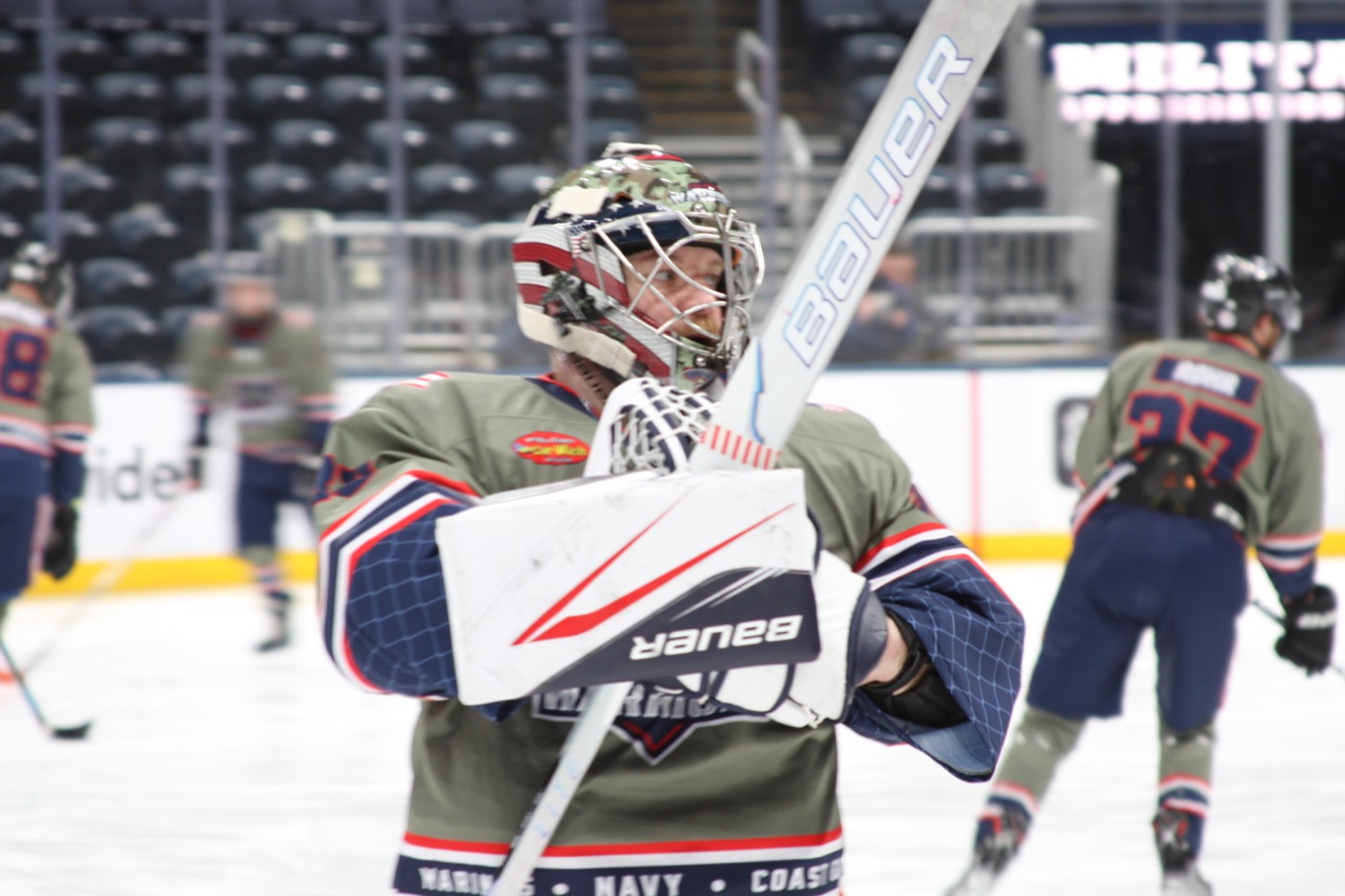 A Columbus Warriors goaltender in the olive home sweater on the ice before a game.