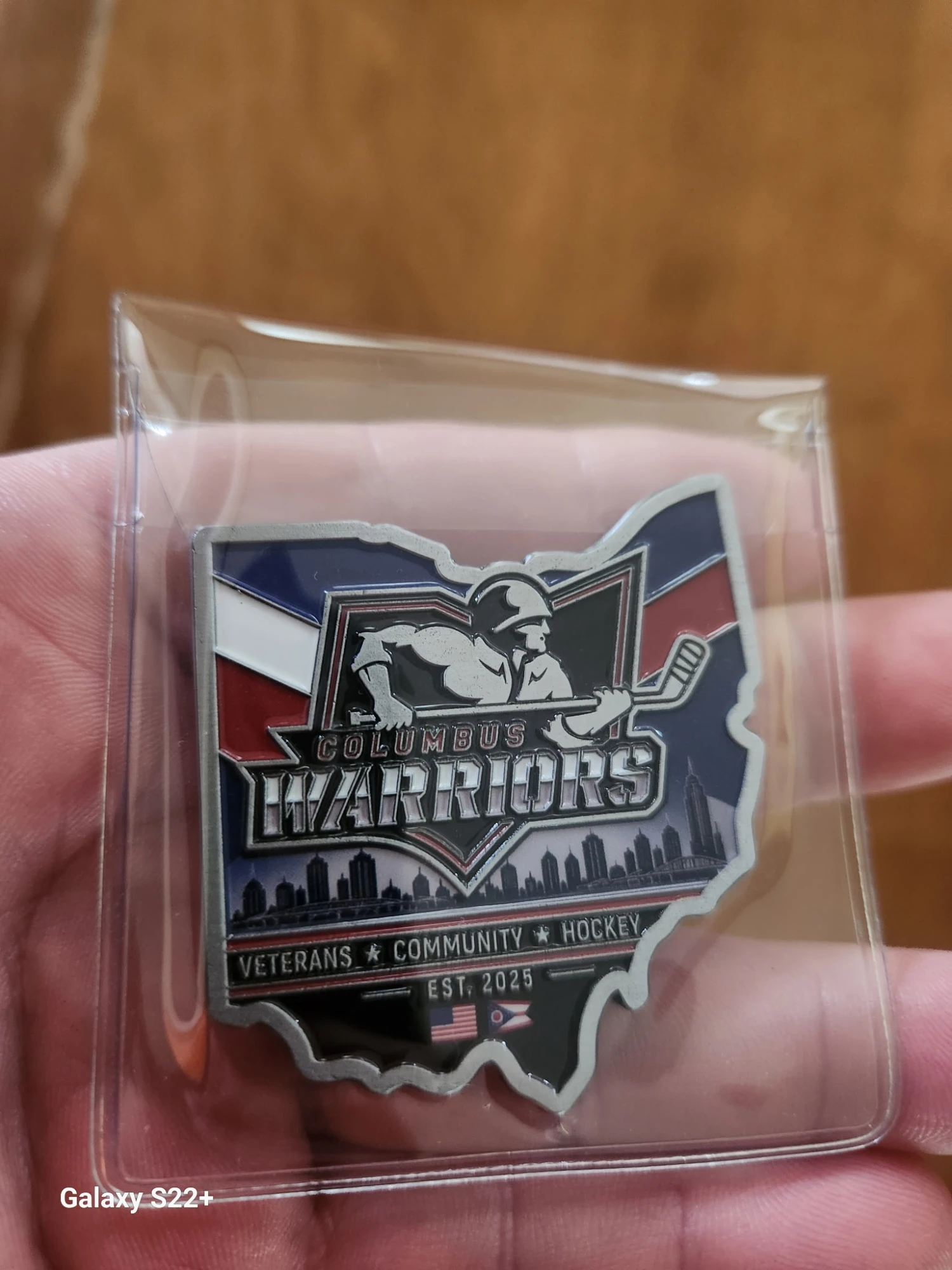 Ohio-shaped Columbus Warriors challenge coin, front: the Warriors logo over the Columbus skyline, with Veterans, Community, Hockey and Est. 2025 beneath.
